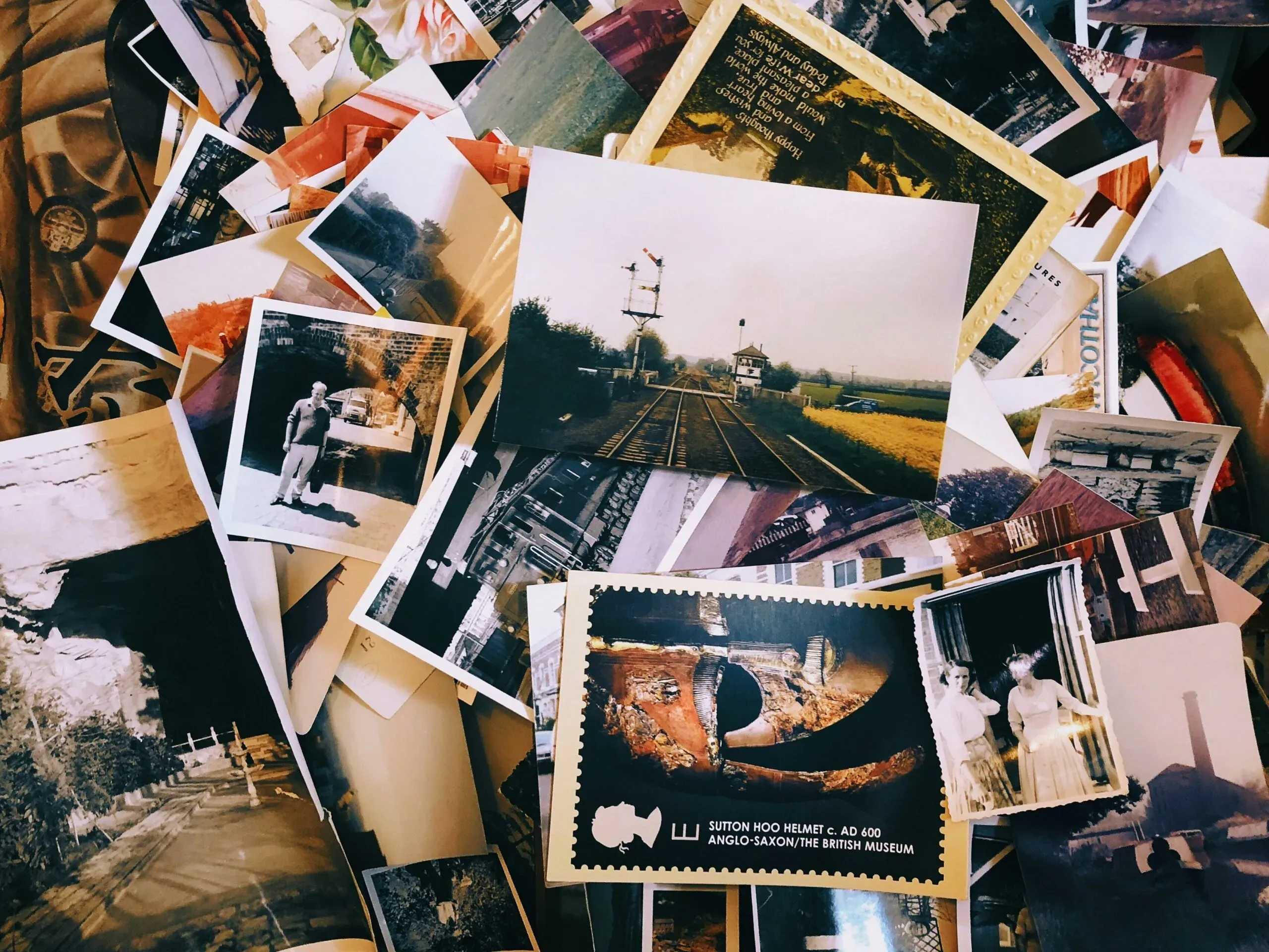 Collection de cartes postales et photos anciennes étalées en pêle-mêle.