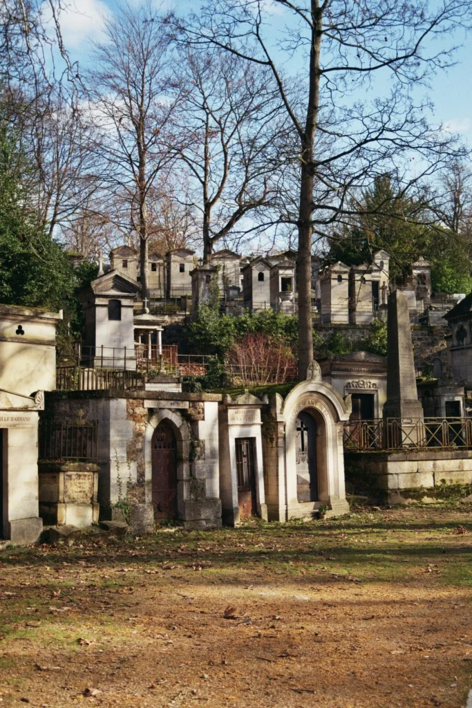Alignement de mausolées et chapelles funéraires anciennes dans un cimetière ombragé.